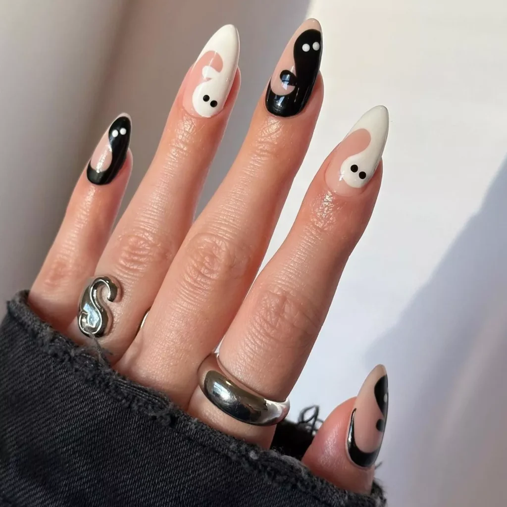 Cute black halloween nails with abstract white ghost designs on almond shaped nails.
