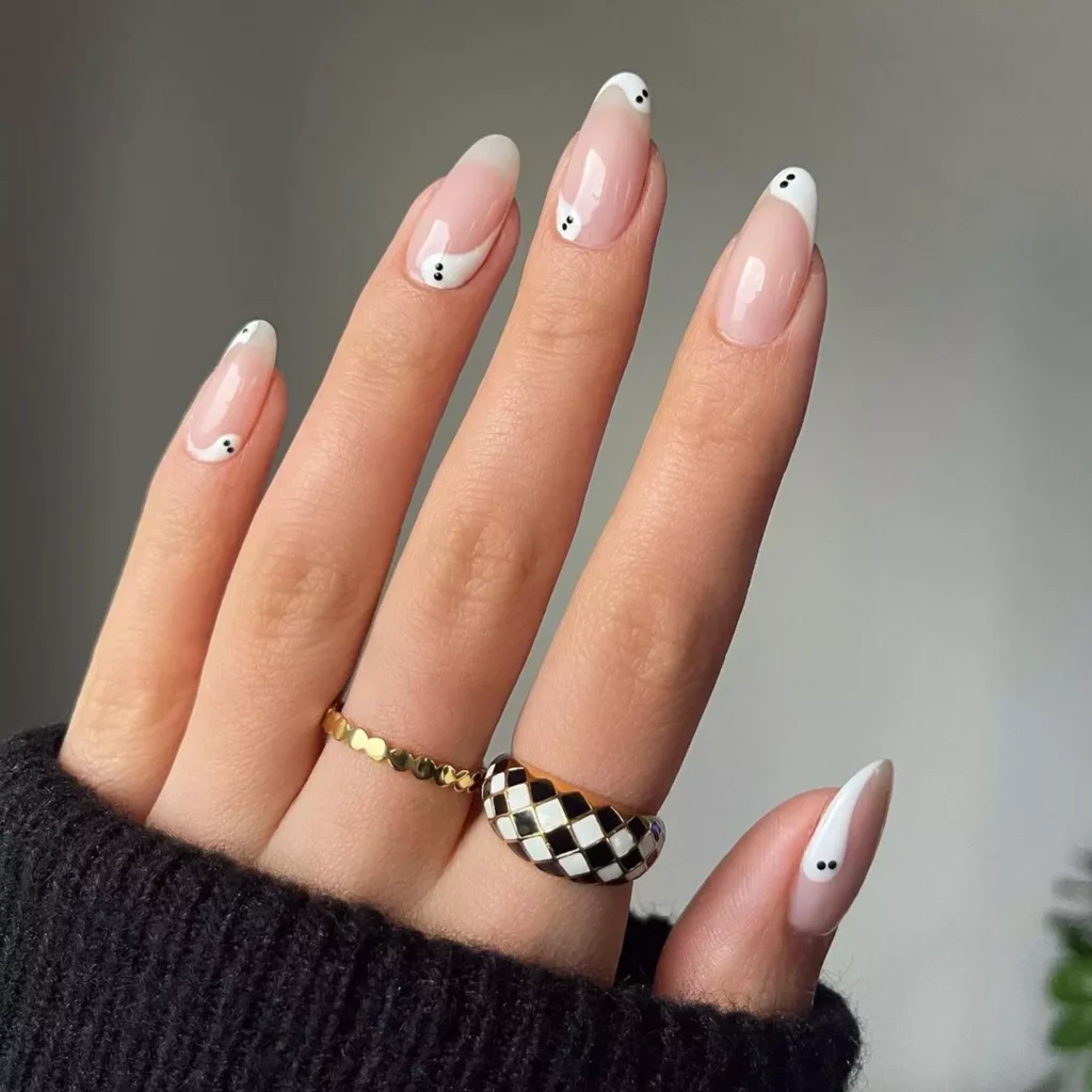 Minimalist black halloween nails with wavy white French tips made to look like ghosts.