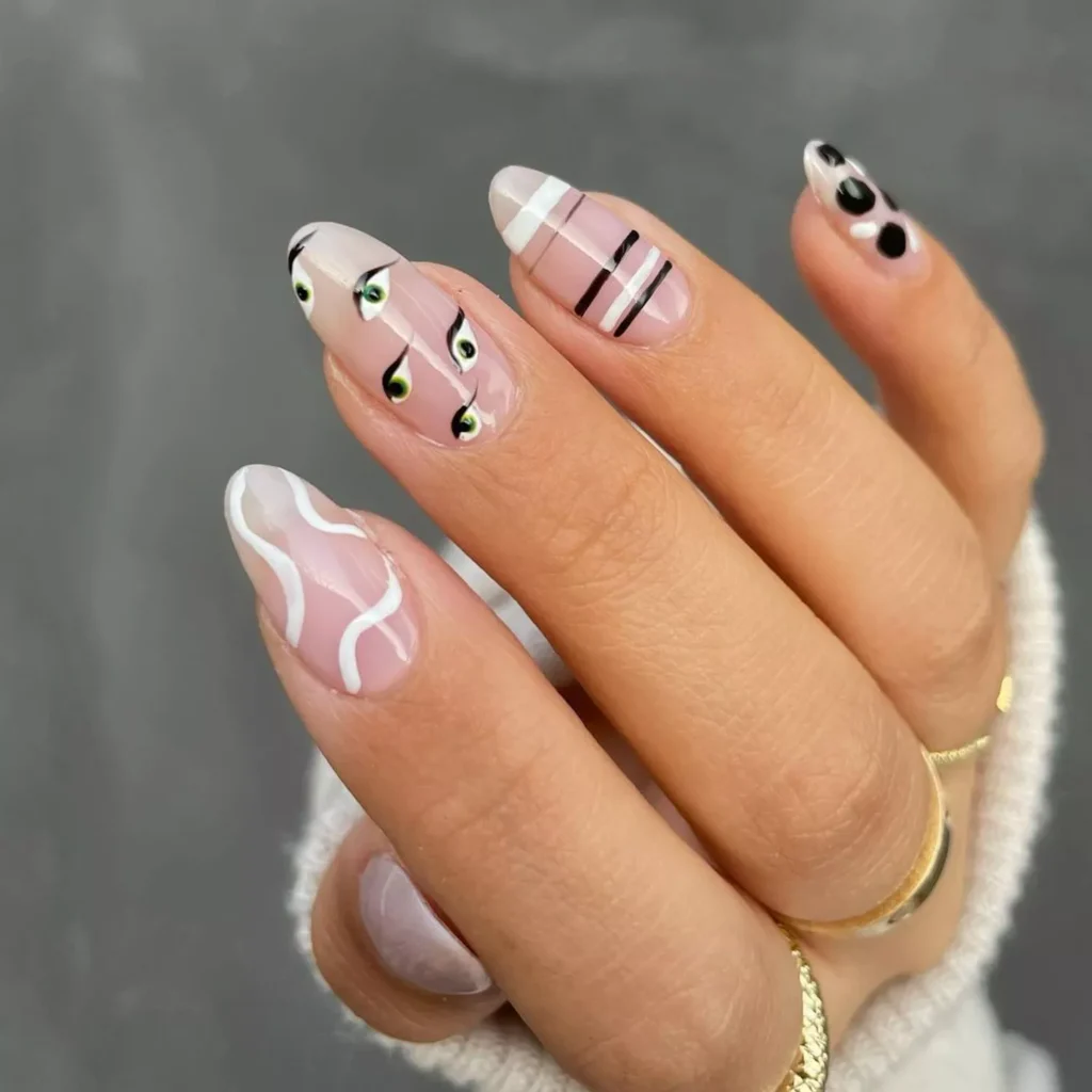 Fun black halloween nails with green eyeballs, stripes, and black polka dots on nude base.