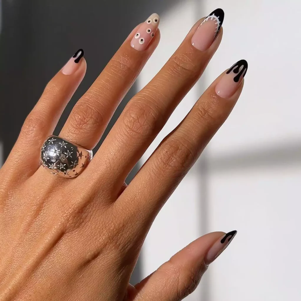 Nude and black halloween nails with dripping French tips and spooky eyeball designs.